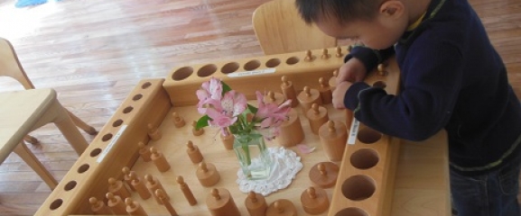 Child is busy working with cylinder shapes at school